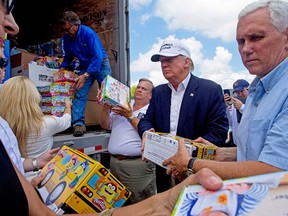 Republican presidential candidate Donald Trump and his running mate, Indiana Gov. Mike Pence, right, help to unload supplies for flood victims during a tour of the flood damaged area in Gonzales, La., Friday, Aug. 19, 2016. (AP Photo/Max Becherer)