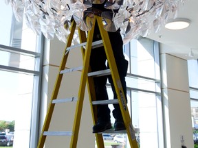 Bob Poczik works on one of the major new lighting fixtures Friday at the newly renovated London Convention Centre. (MIKE HENSEN, The London Free Press)
