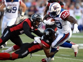 Redblacks Forrest Hightower (centre) and Nick Taylor attempt to tackle Montreal Alouettes running back Brandon Rutley at TD Place. (The Canadian Press)