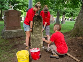 Miranda Leparskas, Kate Schumacher and Andrew Fraser (cct) work on re-setting a tombstone in Woodland Cemetery in London, Ont. on Thursday August 18, 2016. 
The trio are part of a group of summer workers hired by the cemetery to find, repair and re-set old or broken tombstones.
Schumacher, the monument conservation co-ordinator says the cemetery job is "awesome, it's immensely gratifying to put a mark on history...the cemetery is full of life we see deer, wild turkeys, owls and hawks."
Mike Hensen/The London Free Press/Postmedia Network