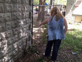Allison Gibson points to the spot she says men from the neighbouring apartment building use as a urinal. (DEREK RUTTAN, The London Free Press)