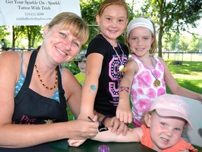 A “Cornfest” Kids Carnival was held at Keterson Park last Saturday, Aug. 20, during which donations were collected for the new Main Street United Church building. Pictured, Trish Laliberte (left) of Sparkle Tattoo Inc. applies a sparkle tattoo to Chloe Illman's arm, while Ashley McLeod and Aubrey Vosper show off Laliberte's previous work. The Mitchell Grizzlies slo-pitch team paid to have Sparkle Tattoo Inc. at the carnival, and a portion of Laliberte's proceeds from the carnival will go back to Main Street United Church. GALEN SIMMONS MITCHELL ADVOCATE