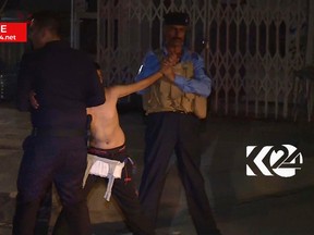 In this still taken from local TV footage, showing a child being restrained by security forces, holding his arms out-stretched as another man cuts off a belt of explosives, Sunday night Aug. 21, 2016, in Kirkuk, Iraq.  Iraqi police say they have apprehended a boy would-be suicide bomber in the city of Kirkuk before he was able to detonate his explosive belt. (Kurdistan 24 TV news via AP)
