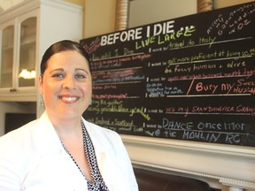 Natasha Girard, the outgoing executive director of Hospice Kingston, stands in their facility in Kingston. Behind her is a board on which people have written things they hope to do before they die. (Michael Lea/The Whig-Standard)