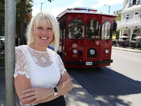 Violette Hiebert, director of marketing and development for Tourism Kingston, stands in front of the Kingston Trolley in Confederation Park. (Elliot Ferguson/The Whig-Standard)