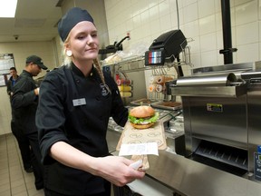 Cook Misty Bimson transfers a finished, customized burger from the preparation area to the front counter as she works as part of a team to make custom ordered burgers as part of McDonalds' new Build A Burger dining option at the Hamilton Road restaurant in London, Ont. on Tuesday May 10, 2016. (Craig Glover/The London Free Press/Postmedia Network)