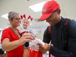 Kirstin Daley holds her daughter Lyla Wheeler, 6, as Damian Warner, Olympic bronze medalist in the decathlon signs her Canadian flag in London airport upon his arrival home on Wednesday August 24, 2016. (MIKE HENSEN, The London Free Press)