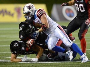 Montreal Alouettes’ Nicholas Shortill (right) tackles Redblacks Tristan Jackson (centre) and Patrick Lavoie at TD Place. (The Canadian Press)