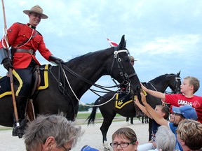 RCMP Const. Steve James, of Sarnia, Ont. smiles as Avery Vanderweide, 7, top right, of Chatham, was among those who took the opportunity to pet his horse Royal, an 18-year-old mare, after the RCMP Musical Ride at the Dresden Raceway in Dresden, Ont. on Wednesday August 24, 2016. Ellwood Shreve/Chatham Daily News/Postmedia Network