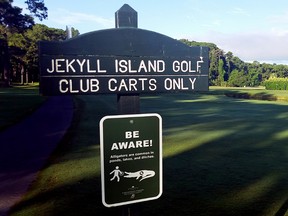 This undated photo provided by Jekyll Island Authority shows a sign warning golfers to “Be Aware” of alligators on Jekyll Island, Georgia. The state park recently placed roughly 30 signs at golf course entrances, ponds and ditches to make sure visitors know the island is home to an abundance of alligators.  (Ben Carswell/Jekyll Island Authority via AP)