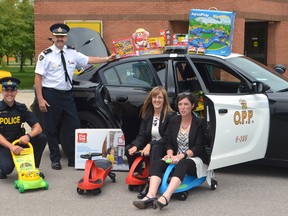 Elgin OPP media officer Const. Adam Crewdson, left, detachment commander Insp. Brad Fishleigh and Det. Sgt. Andrea Quenneville present more than $1,000 of brand new toys to Violence Against Women Services executive director Liz Brown Wednesday. The toys and games, purchased by Elgin OPP officers and staff, will furnish VAWS' new shelter on Princess Ave. which is officially opening on Sept. 7.