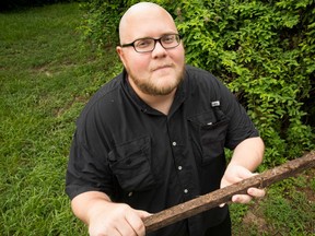 In this August 24, 2016 photo, Kyle Cook holds a stick he stepped on which startled an Eastern diamondback rattlesnake and caused it to bite him in his backyard in Lakeland Fla. Kyle was mowing his grass on Aug. 11 when he was bitten by the snake. Cook is proving to be a survivor. In the last four years, he has been struck by lightning and bitten by a venomous spider. (Ernst Peters/The Lakeland Ledger via AP)