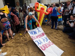 Activists protest outside the French embassy, during the "wear what you want beach party" in London. Writing on the sign reads: 'No to Islamophobia, yes to Burkinis.' (AP Photo/Frank Augstein)