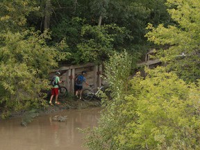 Cyclists navigate high waters while riding at Capilano River near the North Saskatchewan River in Edmonton, Alberta on Thursday, August 25, 2016.