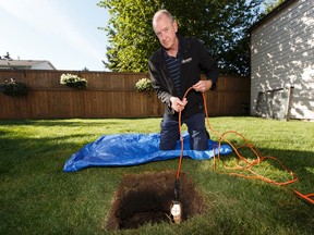 Brian Day lowers a utility light down a well he found in his backyard in south Edmonton, Alberta on Friday, August 26, 2016. The well, which dates from the 1920s, is going to be sealed on Saturday