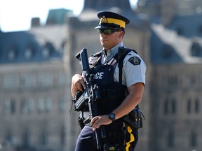 An armed RCMP officer stands on Parliament Hill, a day after an RCMP incident involving Aaron Driver in Strathroy, Ontario, on Thursday, Aug. 11, 2016 in Ottawa. THE CANADIAN PRESS/Justin Tang