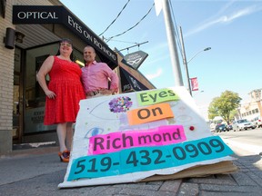 Optician Gayle Harrison and owner Rob Moffatt stand near a homemade sandwich board advertising their store, Eyes On Richmond, at the side of Richmond Street in London, Ont. on Friday August 26, 2016. Moffatt was among the 25 downtown store owners who had their signs taken by bylaw officers earlier this year during a crack down on sign infractions. (CRAIG GLOVER, The London Free Press)