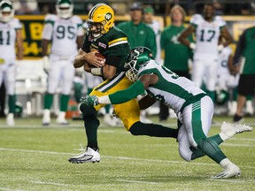 Edmonton Eskimos' quarterback Mike Reilly (13) is tackled by the Saskatchewan Roughriders' Ese Mrabure (98) during second half CFL action at Commonwealth Stadium, in Edmonton on Friday Aug. 26, 2016.