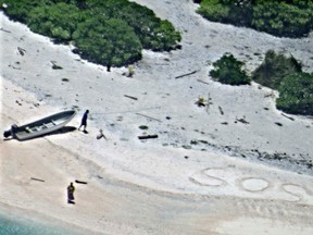 In this Aug. 25, 2016, photo provided by the U.S. Navy, a pair of stranded mariners signal for help as a U.S. Navy P-8A Poseidon aircraft crew from Patrol Squadron (VP) 8 flies over in support of a Coast Guard search and rescue mission on an uninhabited island in Micronesia, Hawaii. The U.S. Coast Guard says the two stranded mariners were rescued Friday after crews saw their "SOS" in the sand. (U.S. Navy via AP)