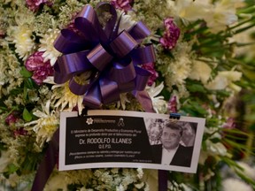 A photo of Bolivia's late Deputy Minister of Internal Affairs Rodolfo Illanes is attached to a funeral wreath, as his remains lie in state at the government palace in La Paz, Bolivia Friday, Aug. 26, 2016. Striking Bolivian miners kidnapped and beat to death Illanes Thursday, in a shocking spasm of violence following weeks of tension over dwindling paychecks in a region hit hard by falling metal prices. The miners were demanding they be allowed to work for private companies, who promise to put more cash in their pockets. (AP Photo/Juan Karita)