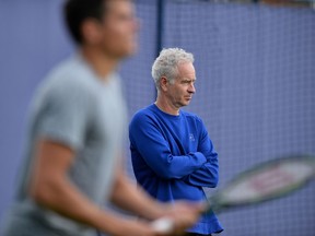 Canada's Milos Raonic is watched by Former US tennis player John McEnroe during a practice session at the ATP tournament at Queen's tennis club, in London in west London on June 13, 2016. (AFP PHOTO/GLYN KIRK)