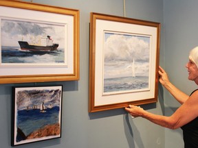 Pieces for the September exhibition at the Lawrence House Centre for the Arts are hung by centre board member Lynne Brogden, including a work in felt (lower left) by Patti Cook and two oil paintings by Alliison Robichaud. Photograph taken Sunday, Aug. 28, 2016 at Sarnia, Ontario (Neil Bowen/Sarnia Observer)
