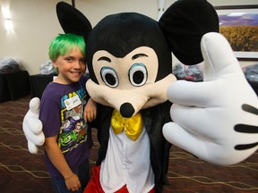 Gavin Dale, 10, (from Fort McMurray, Alta.) poses for a photo with Mickey Mouse after learning that he and 150 other children will receive a trip to Disneyland from Dreams Take Flight Edmonton, at the Doubletree by Hinton West Edmonton hotel, 16615 - 109 Ave., in Edmonton on Sunday Aug. 28, 2016. DAVID BLOOM / Postmedia