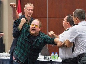 Security guards try to restrain a demonstrator from interrupting the National Energy Board public hearing into the proposed $15.7-billion Energy East pipeline project proposed by TransCanada Monday, August 29, 2016 in Montreal. THE CANADIAN PRESS/Paul Chiasson