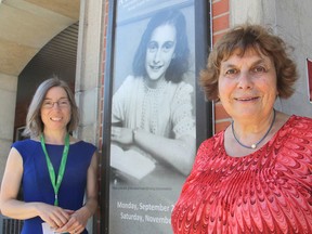 Kimberly Sutherland Mills, left, and Joche Katan stand in front of a poster at the downtown branch of the public library in Kingston, Ont. on Monday, August 29, 2016, announcing a travelling exhibit on Anne Frank will be coming in September. Michael Lea The Whig-Standard Postmedia Network