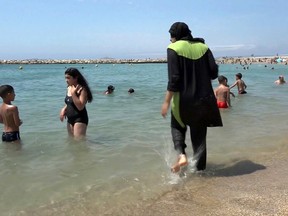 In this Aug. 4 2016 file photo made from video, Nissrine Samali, 20, gets into the sea wearing a burkini, a wetsuit-like garment that also covers the head, in Marseille, southern France. France's top administrative court has overturned Friday Aug. 26, 2016 a town burkini ban amid shock and anger worldwide after some Muslim women were ordered to remove body-concealing garments on French Riviera beaches. (AP Photo, File)