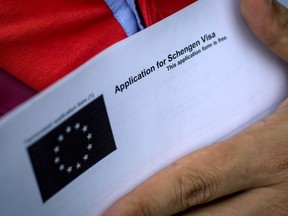 A man holds a Visa application form as he waits in line outside a Joint Visa Application center to apply for a Schengen visa on May 4, 2016 in Istanbul, Turkey. (Photo by Chris McGrath/Getty Images)