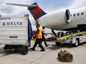 In this July 12, 2016, photo, workers unload baggage from a Delta Air Lines flight at Baltimore-Washington International Thurgood Marshall Airport in Linthicum, Md. Delta Air Lines is rolling out new technology to better track bags throughout its system. (AP Photo/Patrick Semansky)