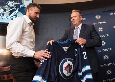 Winnipeg Jets general manager Kevin Cheveldayoff, right, hands Blake Wheeler his new jersey as the new captain for the Winnipeg Jets at a press conference in Winnipeg on Wednesday, August 31, 2016. THE CANADIAN PRESS/David Lipnowski