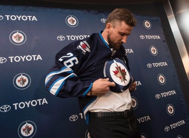 Winnipeg Jets' Blake Wheeler puts on a jersey featuring his new 'C' after being named captain of the Jets during a press conference in Winnipeg on Wednesday, August 31, 2016. THE CANADIAN PRESS/David Lipnowski