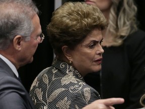 Brazil's Senate leader Renan Calheiros points to an exit as suspended President Dilma Rousseff looks to leave Senate chambers after addressing the lawmakers, at the start of a short recess of her own impeachment trial, in Brasilia, Brazil, Monday, Aug. 29, 2016. Fighting to save her job, Rousseff told senators on Monday that the allegations against her have no merit. "I know I will be judged, but my conscience is clear. I did not commit a crime," she told senators. Rousseff's address comes on the fourth day of the trial. (AP Photo/Eraldo Peres)