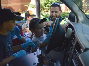 Mohamad El-Hussein, back right, shows children how to use the ambulance sirens at the Chatham-Kent Children's Safety Village. The OPP, CKPS, Fire and EMS were on hand to show children the things they do on a day-to-day basis for the second annual Farm Safety Day.