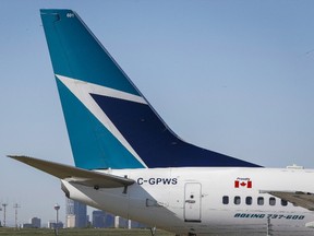 The tail of a WestJet plane dwarfs the Calgary skyline before the airline's annual meeting in Calgary, Tuesday, May 3, 2016. THE CANADIAN PRESS/Jeff McIntosh