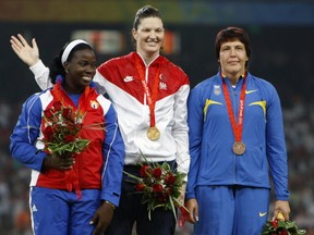 In this Monday, Aug. 18, 2008 file photo, silver winner Yarelys Barrios of Cuba, left, poses on the podium with gold medalist Stephanie Brown Trafton of the U.S, center, and bronze winner Olena Antonova of Ukraine during the awarding ceremony for the women's discus throw in the National Stadium at the Beijing 2008 Olympics in Beijing. (AP Photo/Greg Baker)