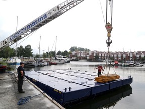 A work crew loads items onto a 12-metre-by-nine-metre barge at Kingston Marina on Wednesday. The barge, along with another one, will be used on the Cataraqui River at the proposed site of the third crossing to drill some test holes. The work will take a little over a month to complete. The barge should be on site by early next week. (Ian MacAlpine/The Whig-Standard)