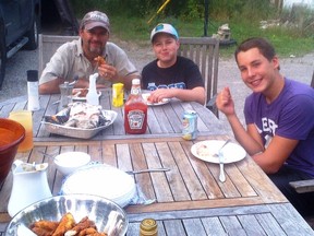 Sudbury Star fishing columnist Frank Clark (left) enjoys some pan fried bass with his stepson Morgan and Morgan's buddy Ryan at his home on the Vermillion River. Jackie Clark/For The Sudbury Star