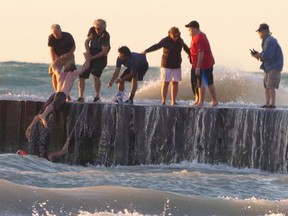 Members of the public pull a man out of the water at the Grand Bend beach on Aug. 31st. The man and a woman were saved by bystanders after they became overwhelmed by the rough waters and called out for help. (Photo courtesy of Emsie WIlliams)