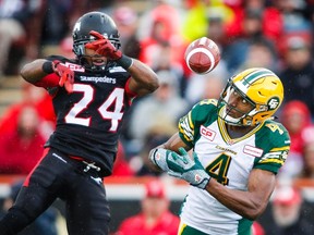 Edmonton Eskimos' Adarius Bowman, right, juggles a pass as Calgary Stampeders' Joe Burnett looks on during second half CFL football action in Calgary, Monday, September 7, 2015. THE CANADIAN PRESS/Jeff McIntosh