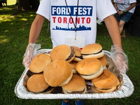 A volunteer carries a tray of hamburgers at a party thrown by Rob Ford's family called Ford Fest in Toronto on Friday, July 25, 2014. THE CANADIAN PRESS/Darren Calabrese