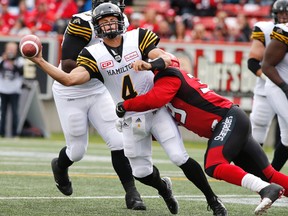 Hamilton Tiger-Cats’ quarterback Zach Collaros, left, gets the ball away just as he is tackled by Calgary Stampeders defensive lineman Charleston Hughes in Calgary Sunday, Aug. 28, 2016. (THE CANADIAN PRESS/Larry MacDougal)