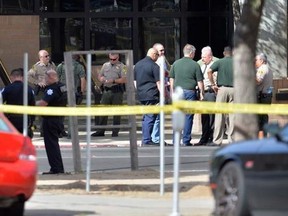 Law enforcement officials and others are seen outside the lobby of the Fresno County Jail after reports of an active shooter in the main lobby of the jail in downtown Fresno, Calif., Saturday, Sept. 3, 2016. Two unarmed officers were critically injured after being shot by a visitor in the lobby of the central California jail, authorities said Saturday. Authorities said officers from the secured areas inside the jail ran to the lobby, where a lieutenant fired shots at the gunman, identified as 37-year-old Thong Vang, who was taken into custody. (Silvia Flores/The Fresno Bee via AP)