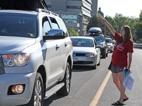 Student volunteer Jenna D'Aurizil directs traffic on Union Street during Queen's University move-in day in Kingston, Ont. on Sunday September 4, 2016. Steph Crosier/Kingston Whig-Standard/Postmedia Network