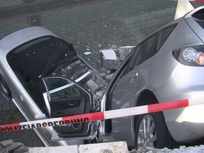 In this Sept. 5, 2016 picture the crash scene in a car parkin Bottrop, Germany. An 80-year-old woman took an unintended short cut as she tried to drive her car , right, out of a multistory car park in Germany, breaking though the building’s wall and landing on a parked convertible 3 meters (10 feet) below. Police said that neither the driver nor her 85-year-old husband, who was standing next to the car at the time, were hurt in the accident in Bottrop late Monday.  (Daniel Knopp /News-Report-NRW/dpa via AP)