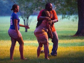 A man holds a woman at the scene of a double shooting in Ogden Park, Monday, Sept. 5, 2016, in the Englewood neighborhood of Chicago. Thirteen people were shot to death over the Labor Day weekend in Chicago, making it the deadliest holiday weekend of one of the deadliest summers the city has experienced in decades. (Erin Hooley/Chicago Tribune via AP)