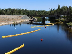 Booms designed to collect oil on the water surface are seen near the bridge where a Canadian National Railway train derailed more than a year ago, causing nearly one million litres of oil to spill into the Makami River.