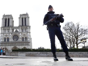 In this March 27, 2016 file photo, a French police officer stands guard as worshipers arrive for the Easter mass at Notre Dame Cathedral, in Paris. Police officials say Wednesday, Sept. 7, 2016, a terrorism investigation is under way into seven gas canisters found in a car parked near Notre Dame Cathedral in Paris. (AP Photo/Francois Mori, File)